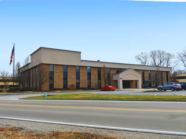 Exterior view of Magnolia Health Systems building with flag, cars, and blue sky.