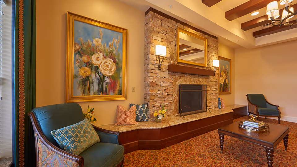 Cozy living room with a stone fireplace, seating, artwork, and warm decor.