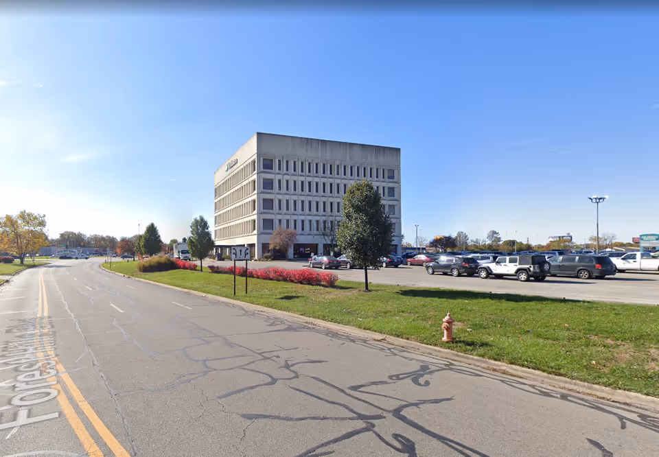 Exterior of a large white building with a parking lot and blue sky.