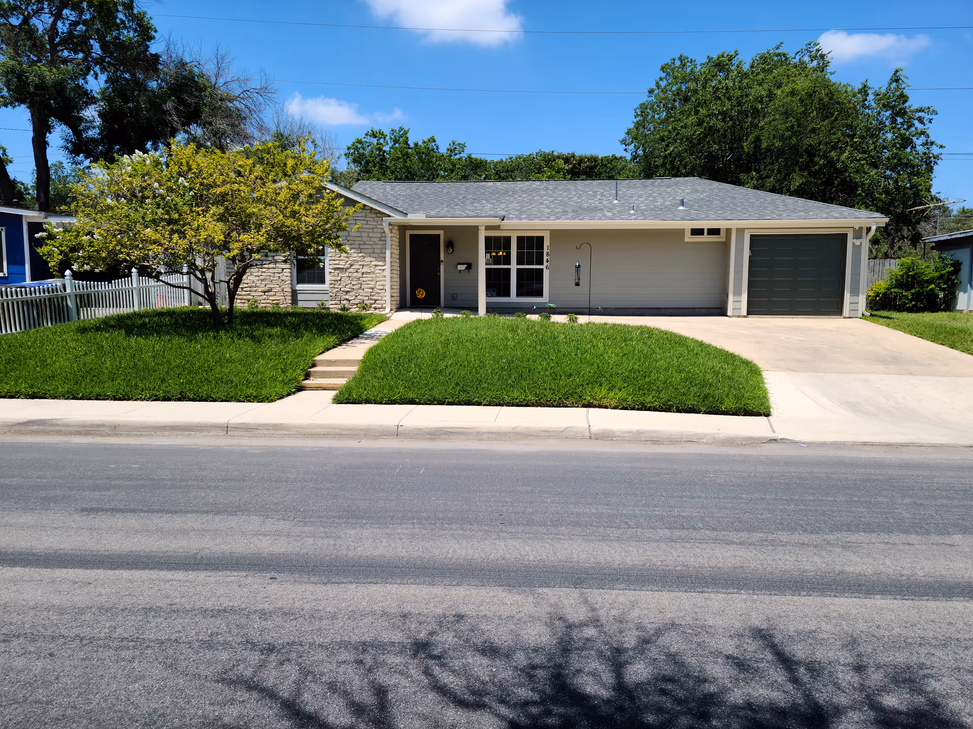 Front view of a single-story residential facility with lawn, driveway, and two-car garage.