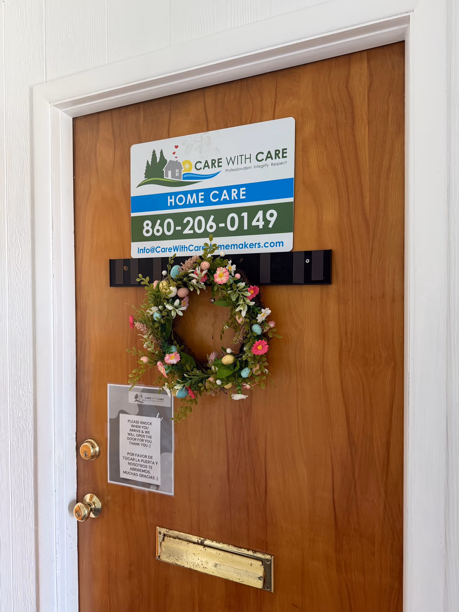 Wooden interior door featuring a Care with Care Homemakers sign and wreath