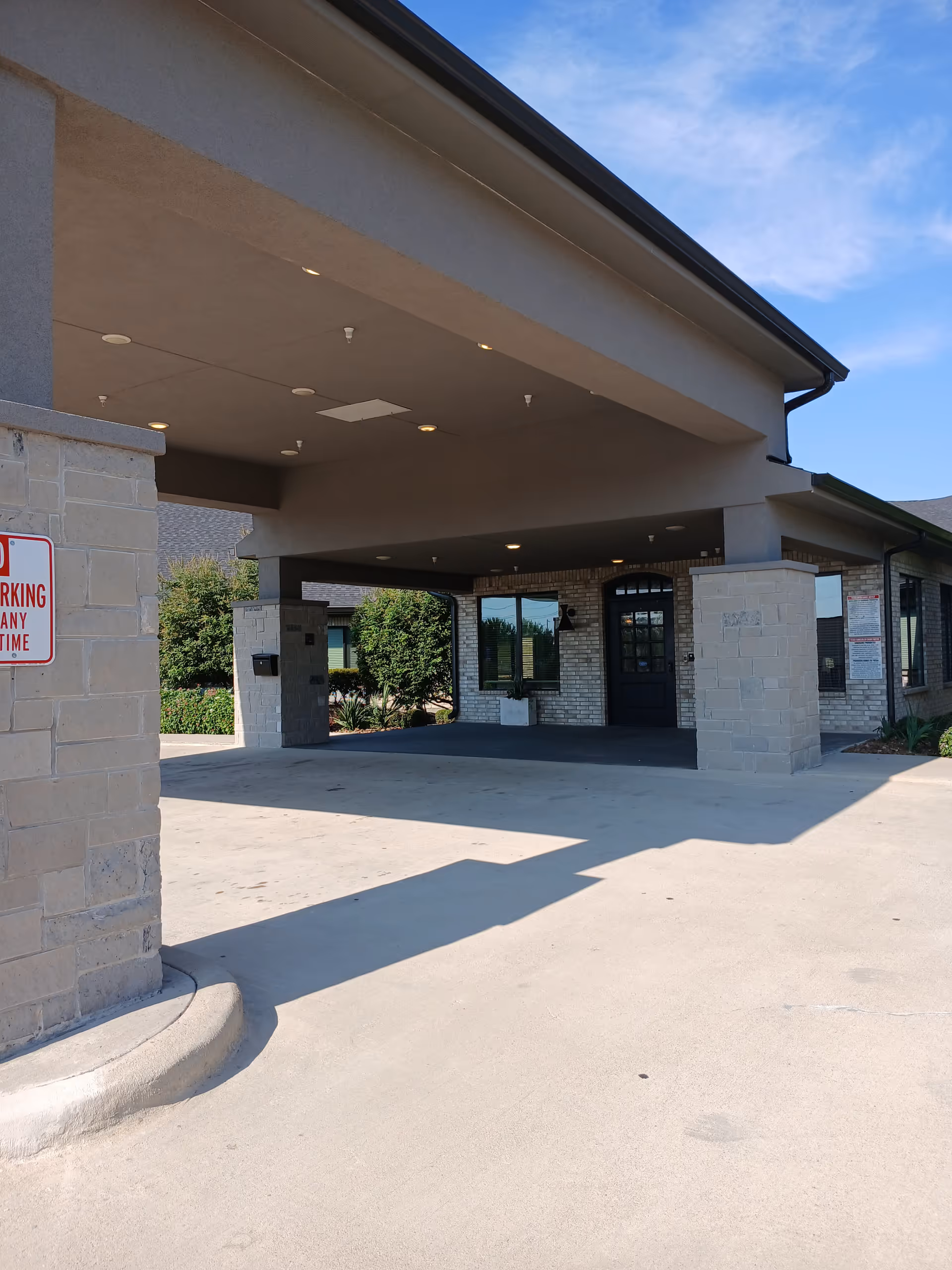 Exterior entrance of a senior care facility with a covered drop-off area.