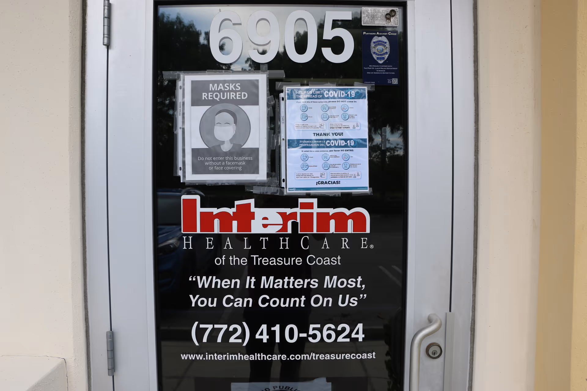 Glass door entrance with Interim HealthCare signage and a 'Masks Required' poster.