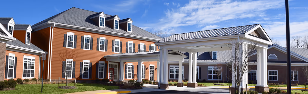 Exterior view of a senior living facility with a covered entrance and orange siding.