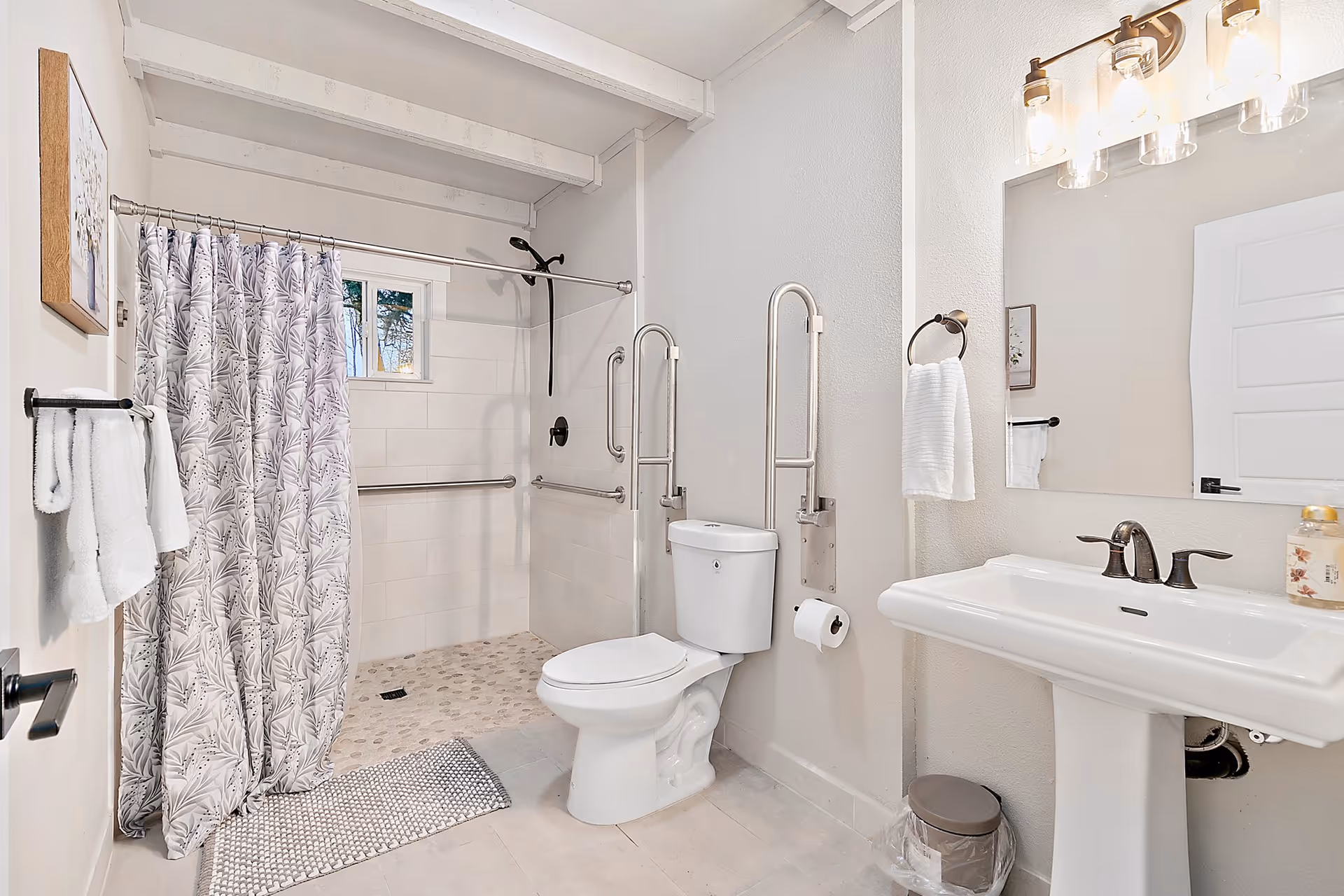 Accessible bathroom with shower, toilet, sink, and safety grab bars.