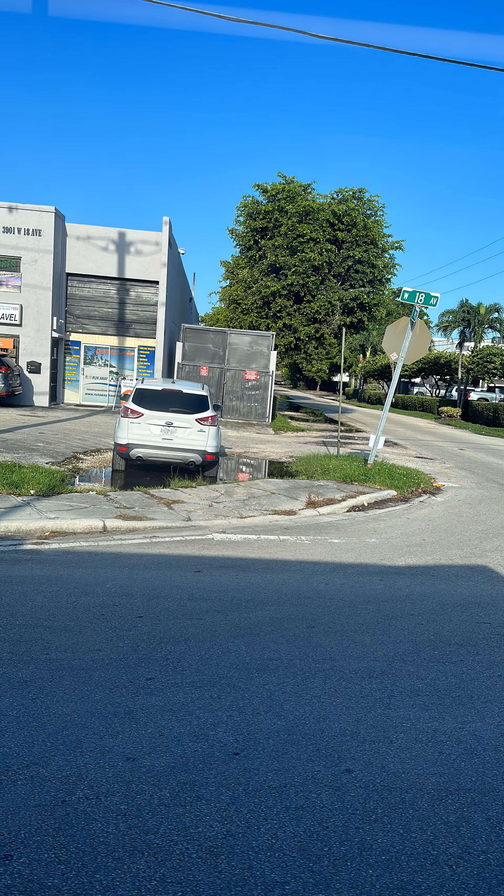 Street corner view showing a white SUV parked beside a building facade.