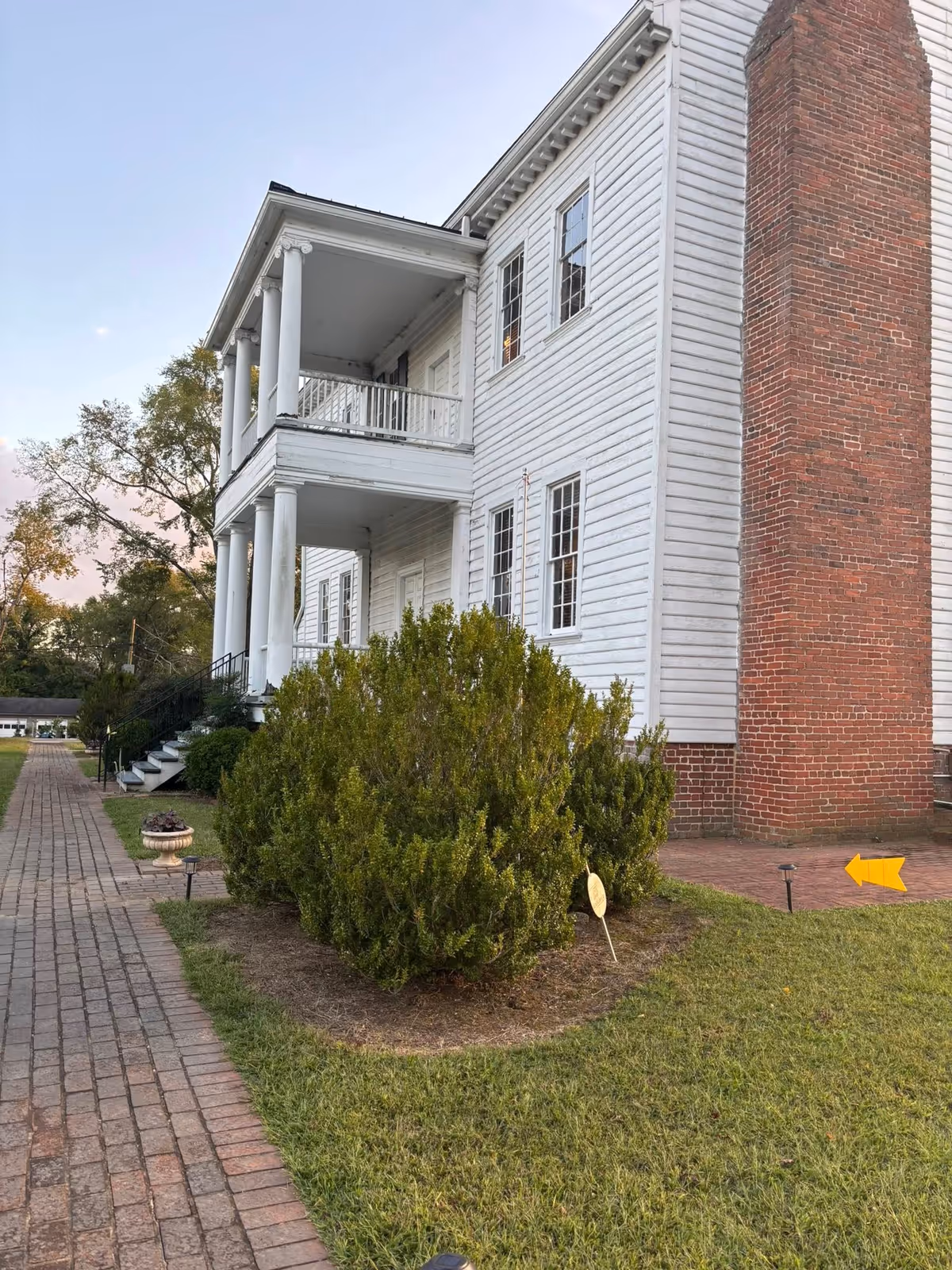 White two-story retirement center with columns, porches, brick chimney, and surrounding lawn.