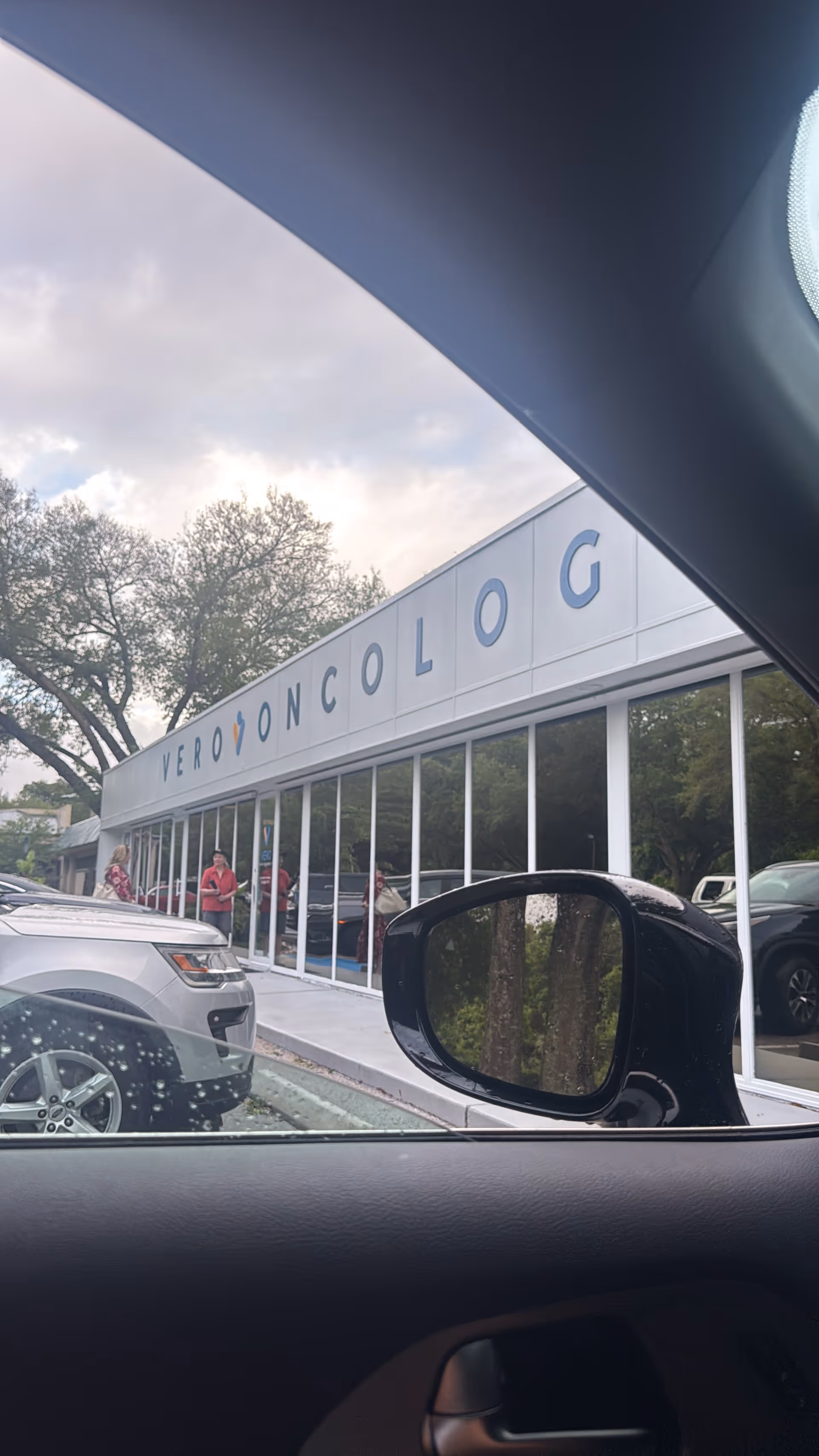 Exterior view of a storefront-style building with glass windows and people outside.