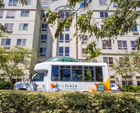 Exterior view of The Plaza at Punchbowl building with a parked senior living shuttle bus.