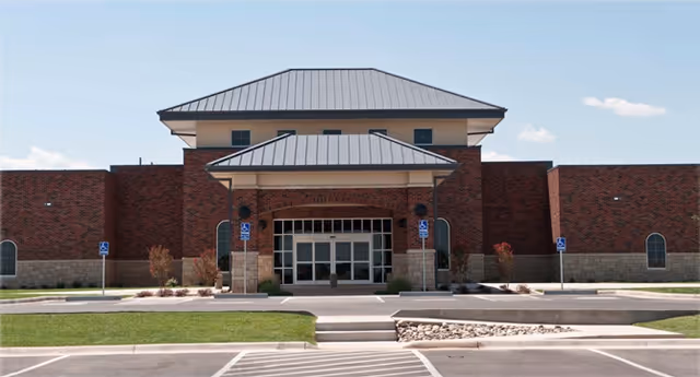 Front exterior of brick medical center with glass doors, covered entrance, and handicapped parking.