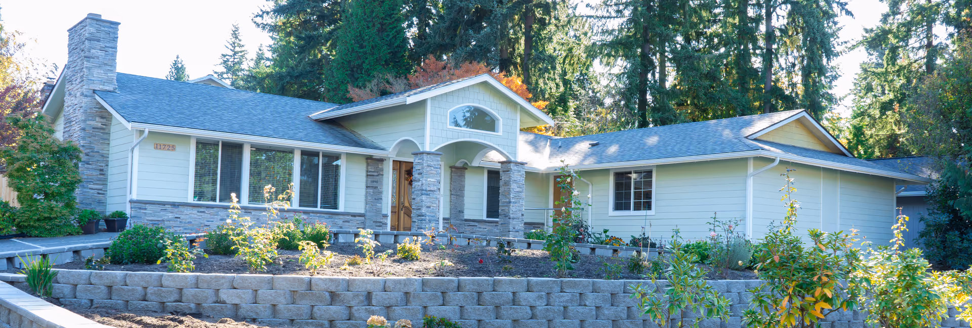 A single-story senior care facility exterior with stone accents and tiered landscaped front yard.