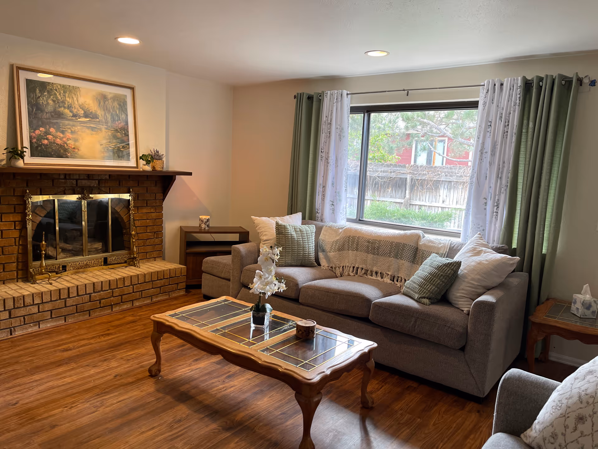 Cozy living room with brick fireplace, sofa, coffee table, and window view.