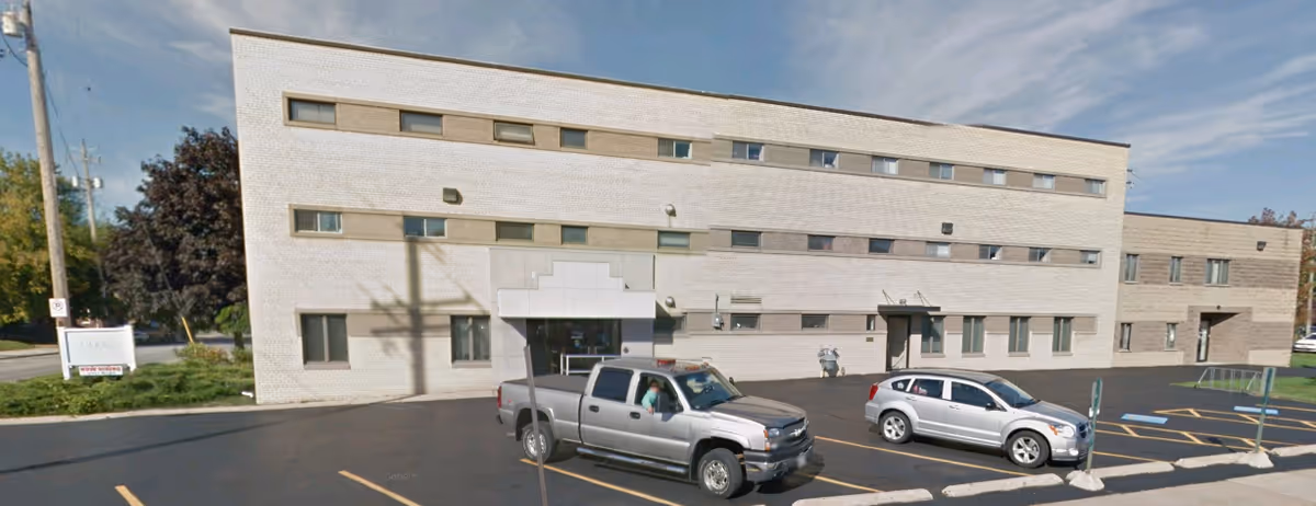 Exterior view of Clarity Care facility with a parking lot and two vehicles.