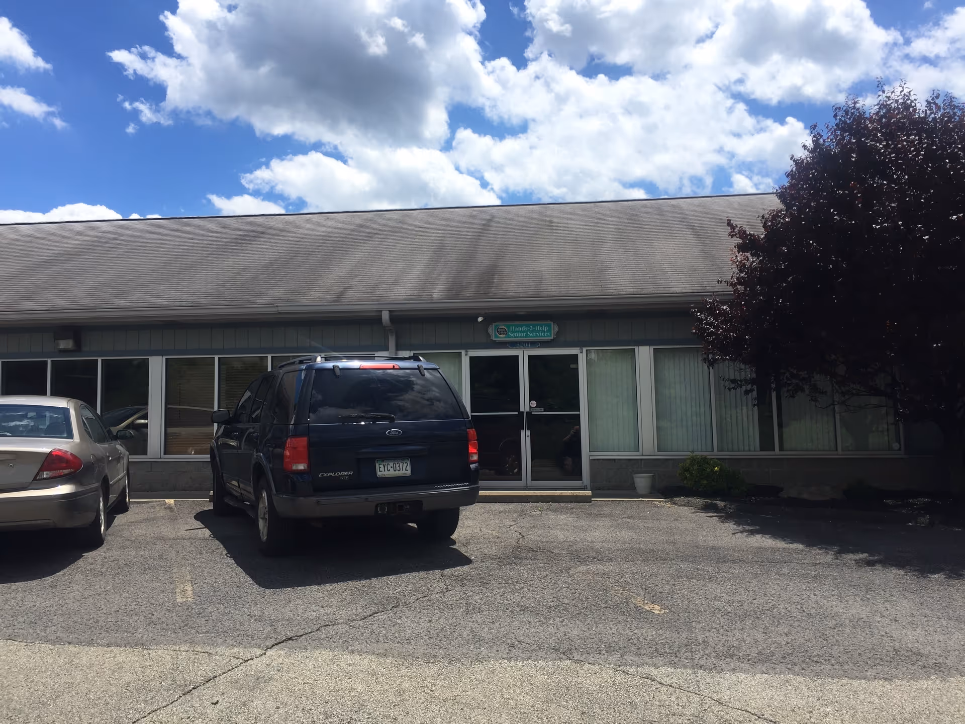 Front view of Hands-2-Help Seniors Services building with parked cars in lot