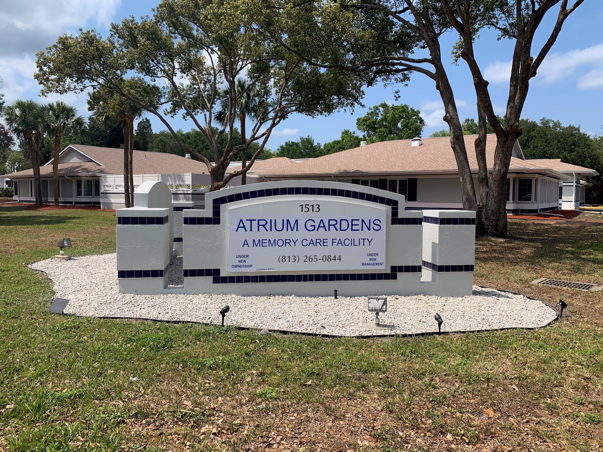 Exterior view of the Atrium Gardens sign with landscaped grounds and single-story buildings.
