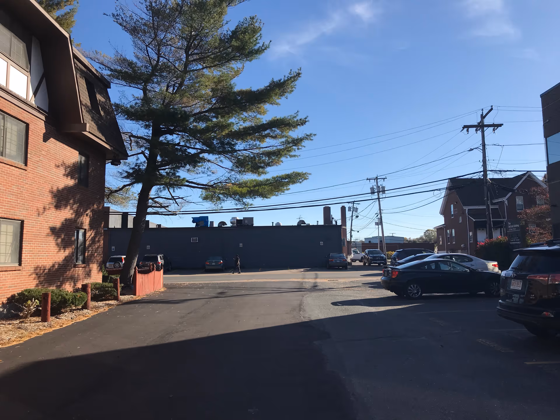 Exterior view of a brick building and parking lot with several cars.
