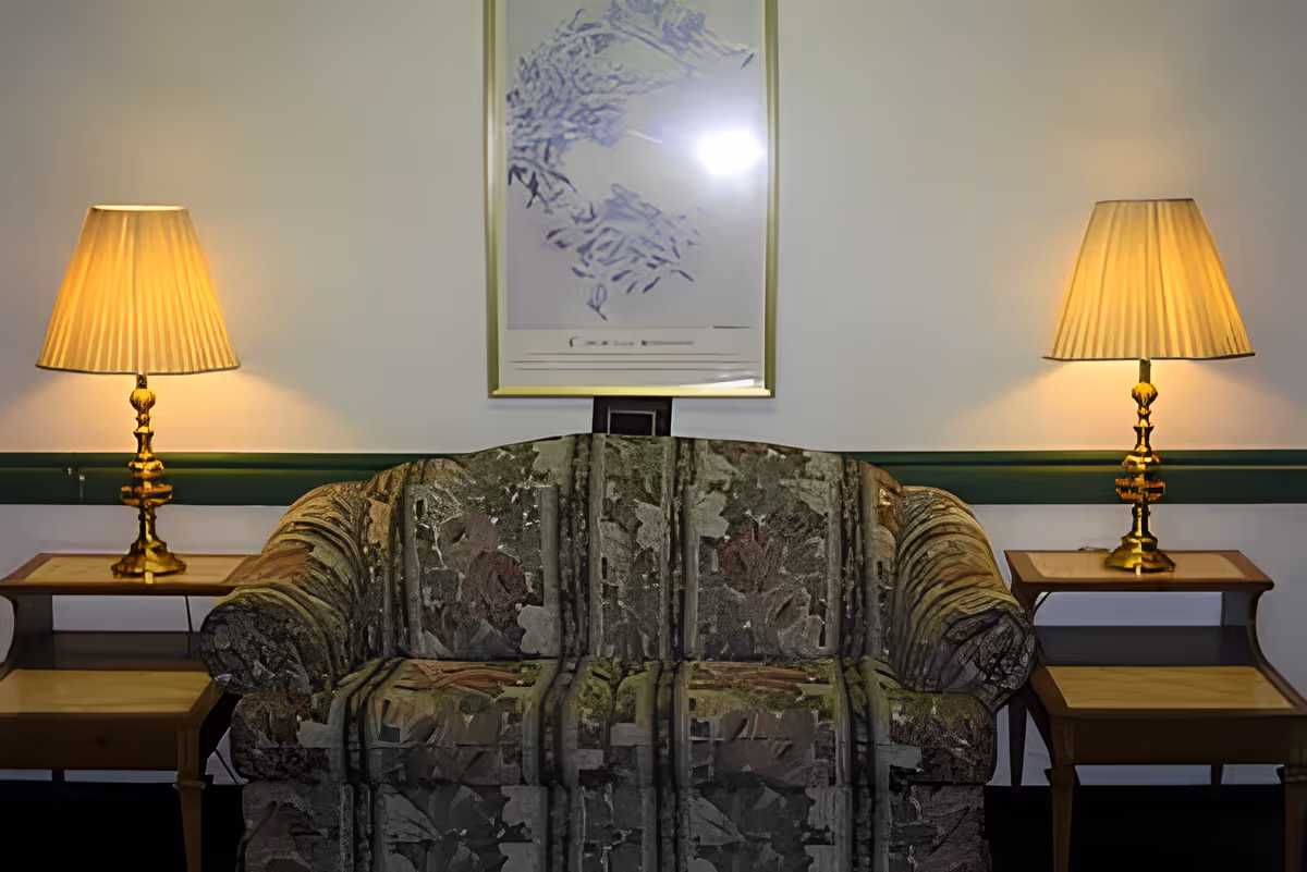 Upholstered couch flanked by two lit table lamps on side tables beneath a framed picture on the wall.