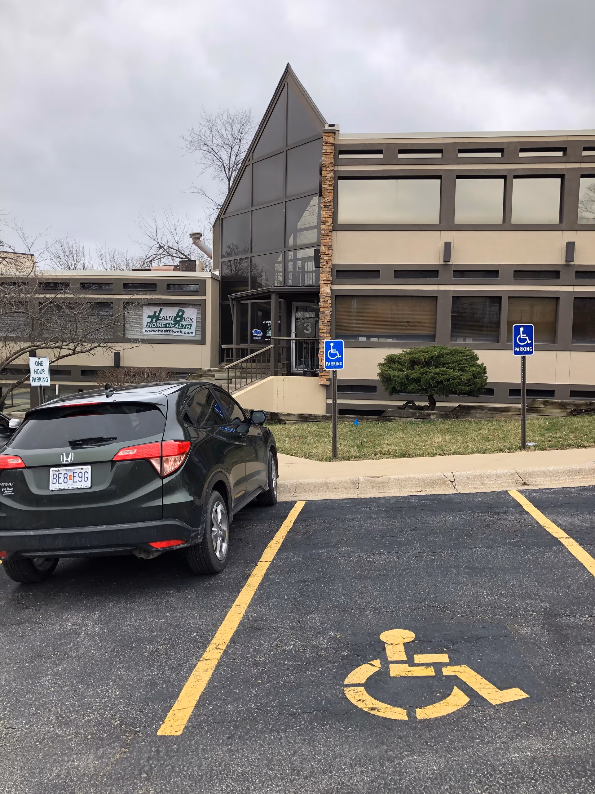 Front exterior of a modern senior facility with handicap parking and glass entrance.