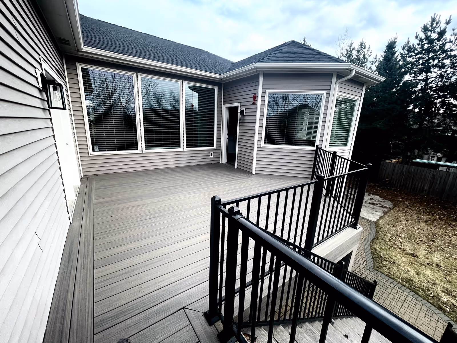 Exterior view of a gray facility with a large wooden deck and railing.