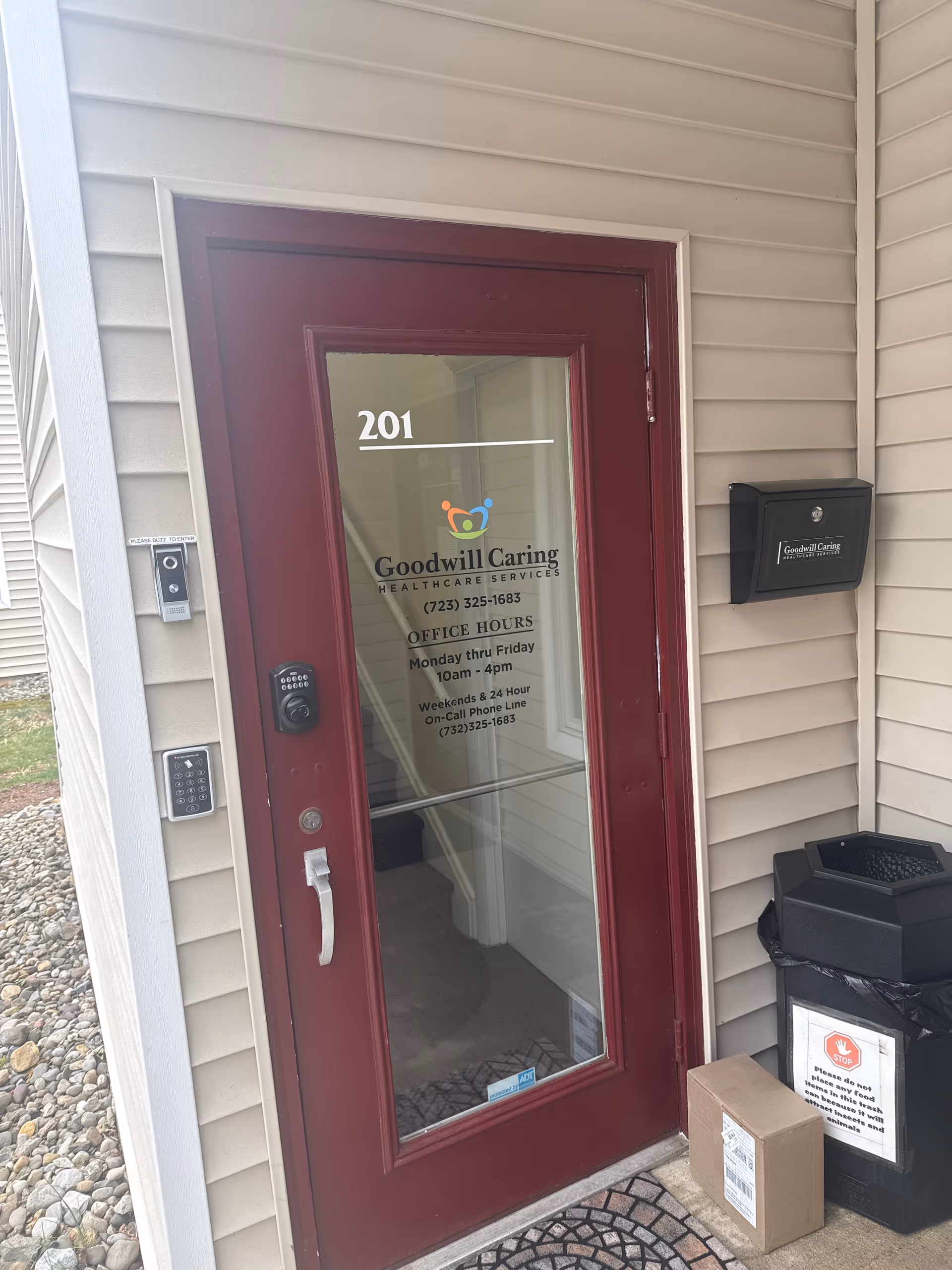 Maroon glass door entrance for Goodwill Caring Healthcare Services with logo and office hours.