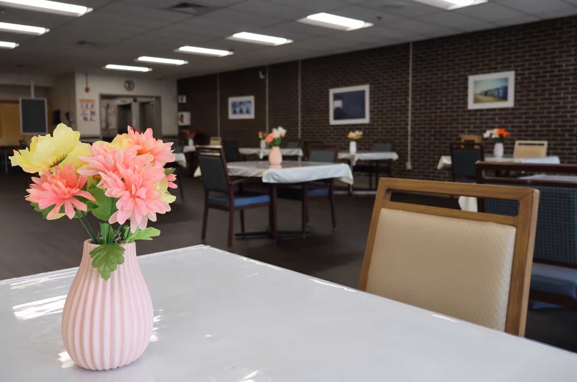 Pink flower arrangement on a table in a spacious dining hall.