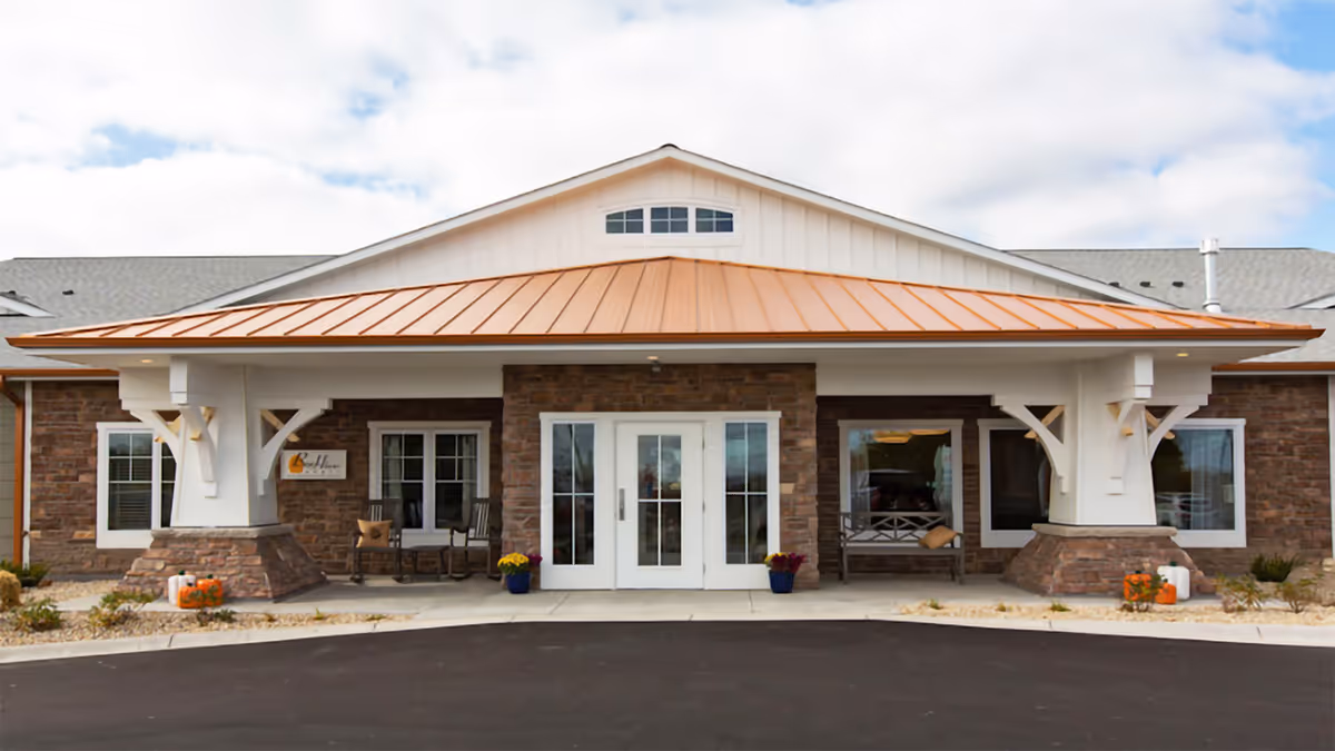 Front exterior of Bee Hive Homes Maple Grove with brick facade, white columns, and glass doors.