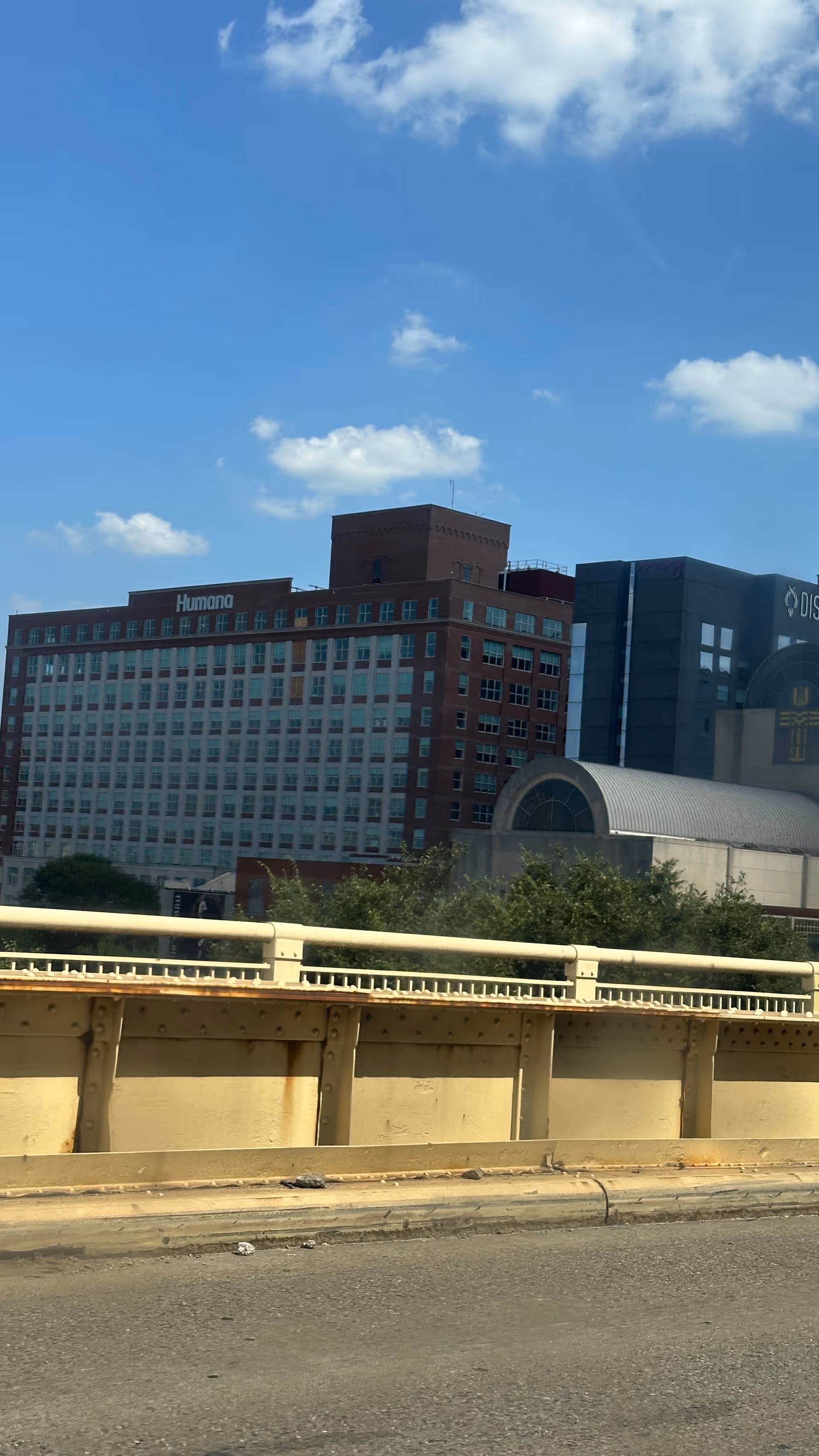 Cityscape with tall brick buildings, a highway barrier, and blue sky.