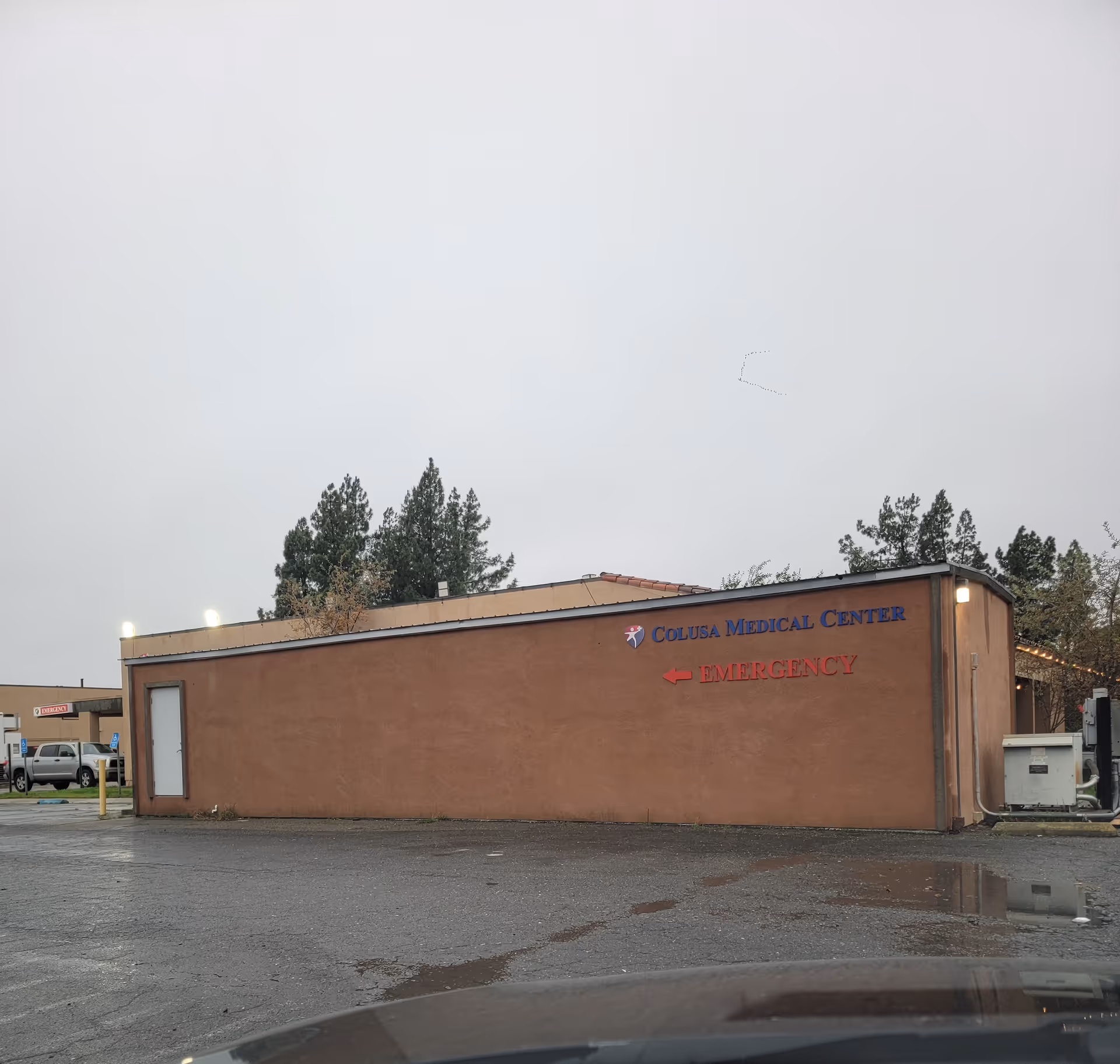 Exterior of Colusa Medical Center with red emergency sign on brown wall.
