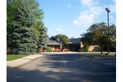 Exterior view of Willowbend Living Center with driveway, trees, and parking lot.