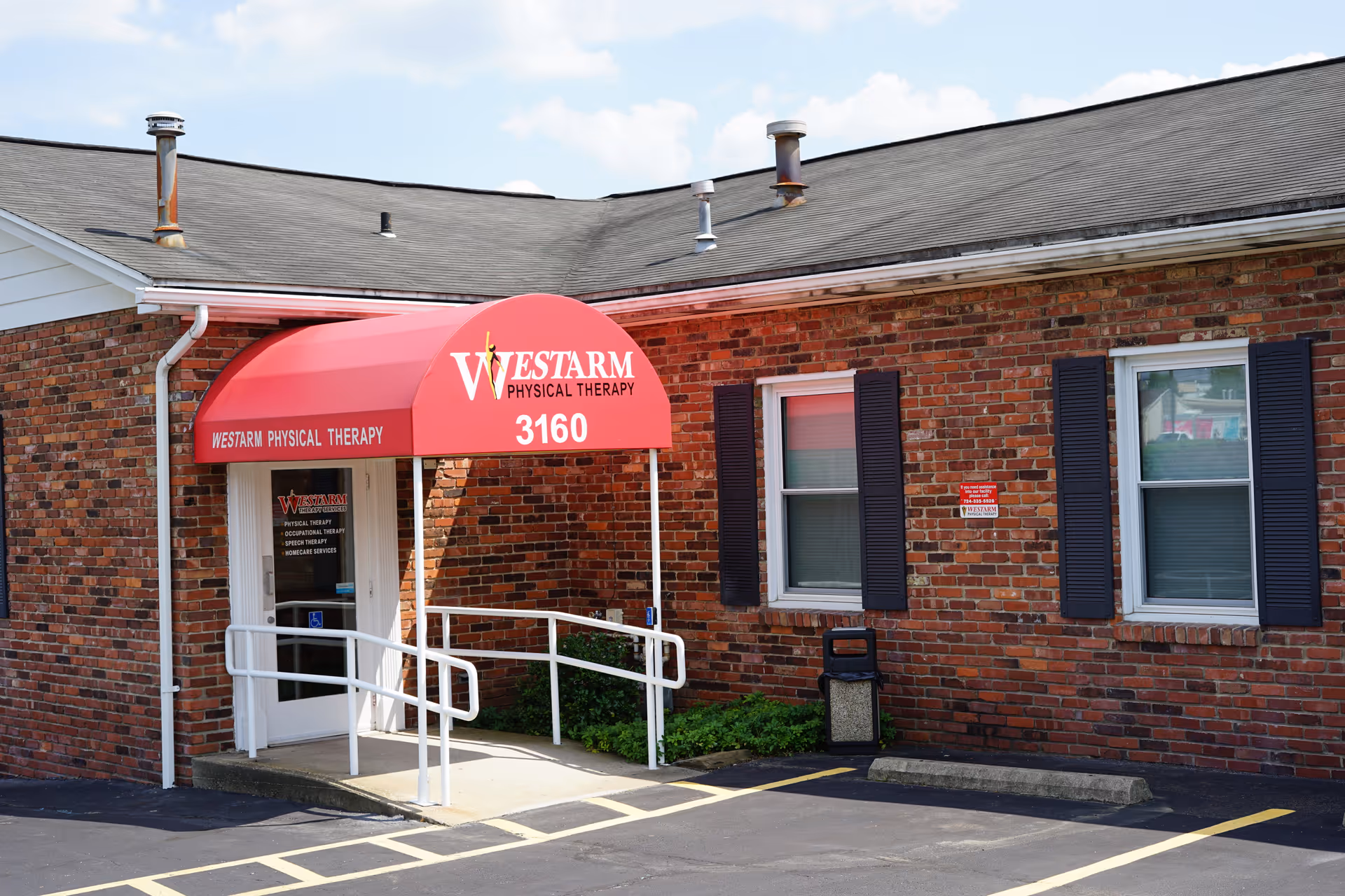 Brick building exterior with red canopy reading WESTARM Physical Therapy over entrance.