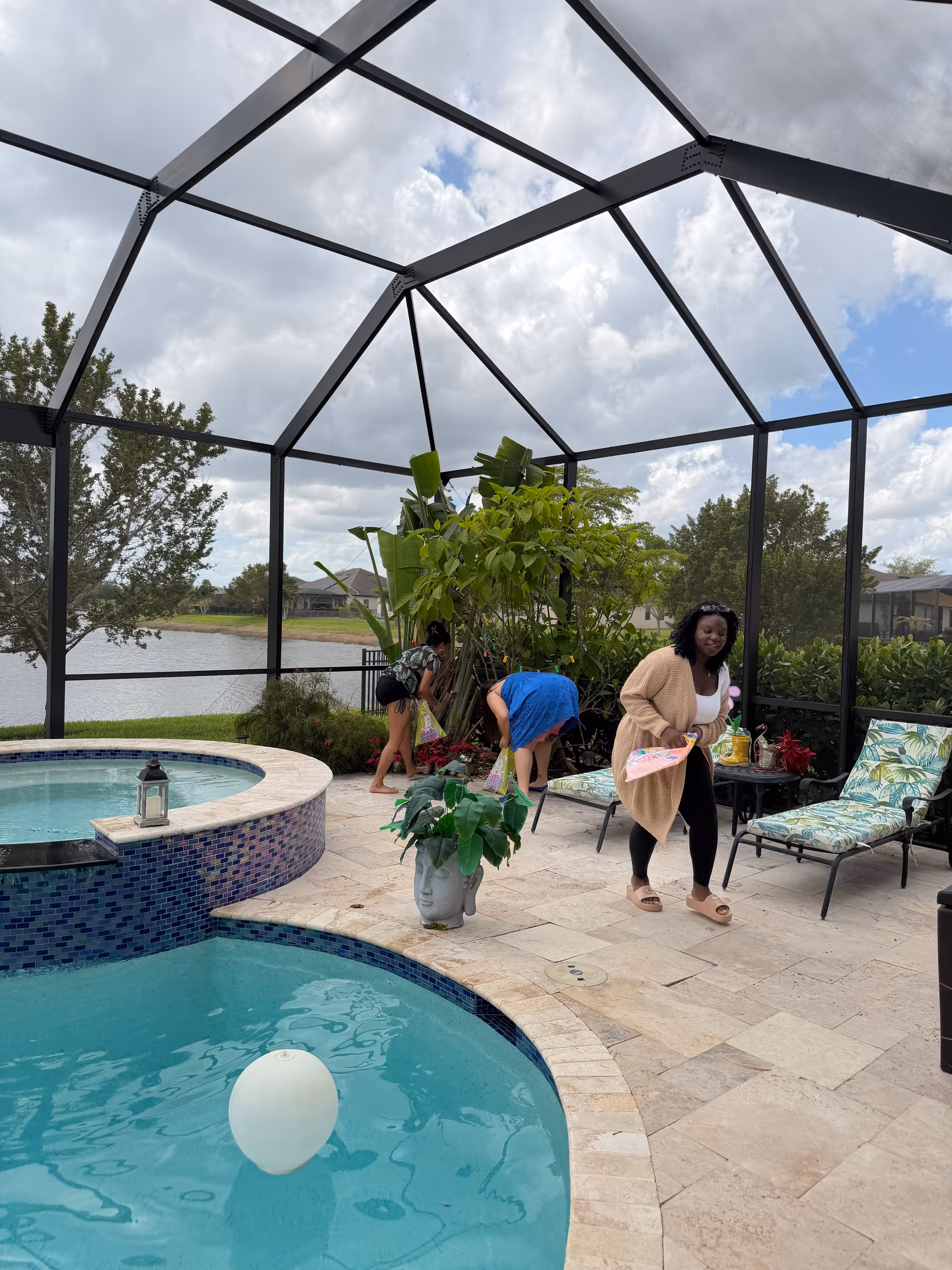 Outdoor screened pool area with residents and caregivers near lounge chairs.