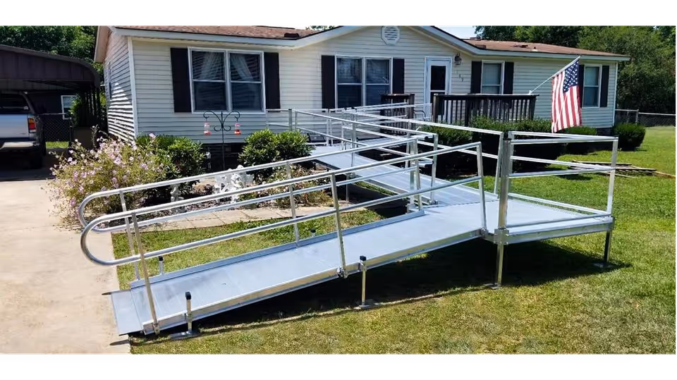 Metal ramp with rails leads to the front entrance of a white house.