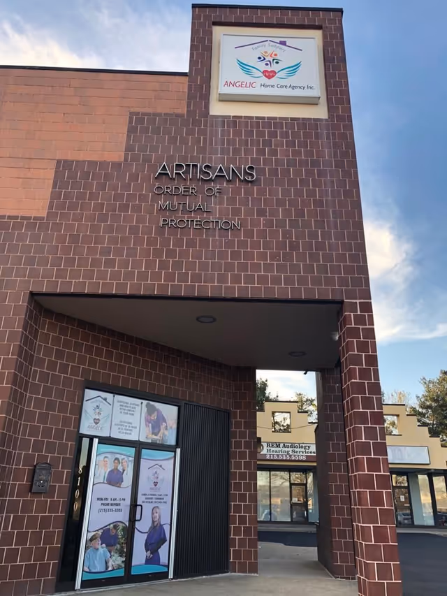 Exterior brick building front with Angelic Home Care Agency sign above entrance and posters on doors.