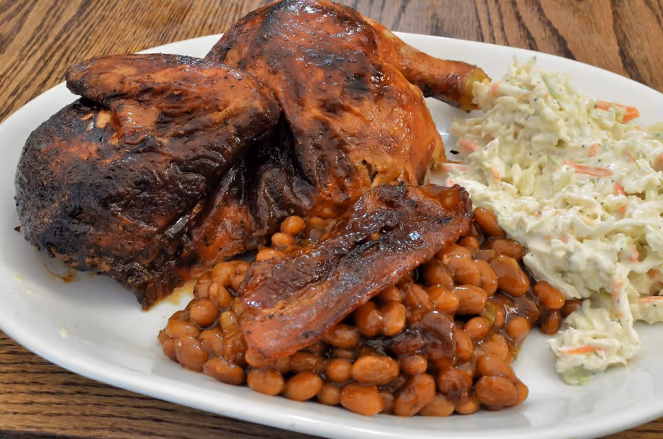 Plate of roasted turkey, beans, and coleslaw on a wooden dining table.