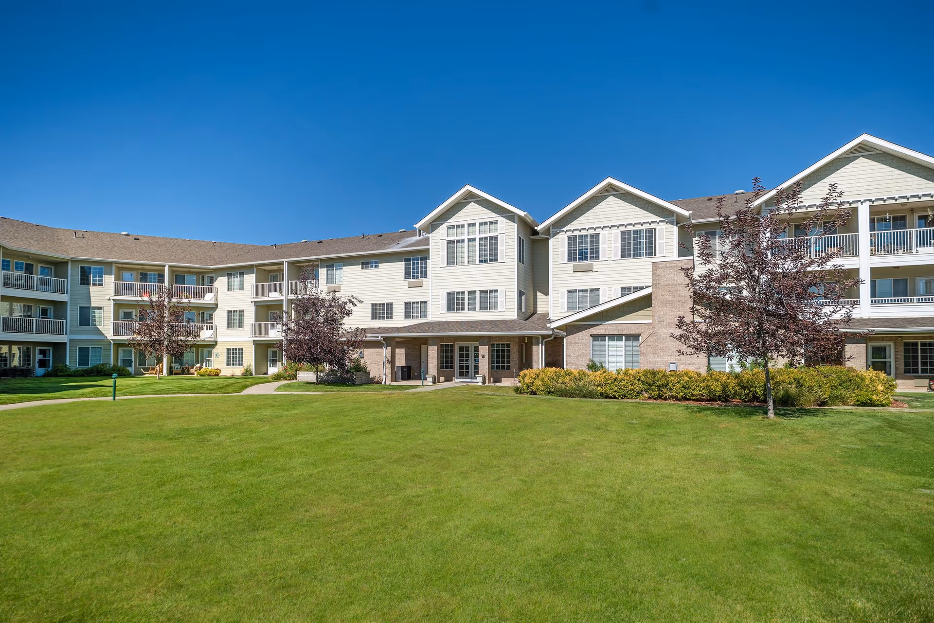 Exterior view of Highland Trail senior living facility with beige siding and manicured lawn.