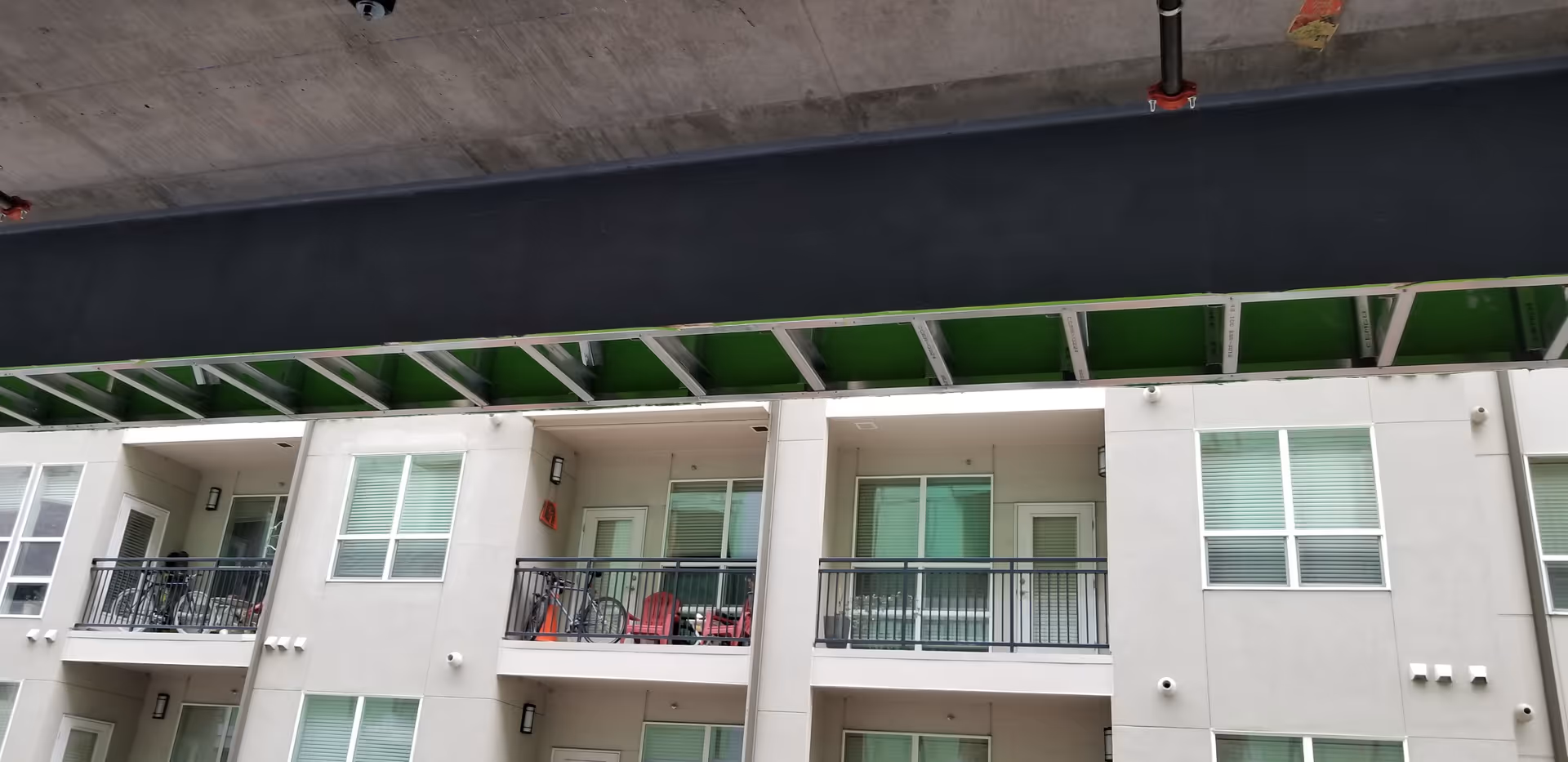 Exterior view of a multi-story senior living building with balconies and an overhead structure.