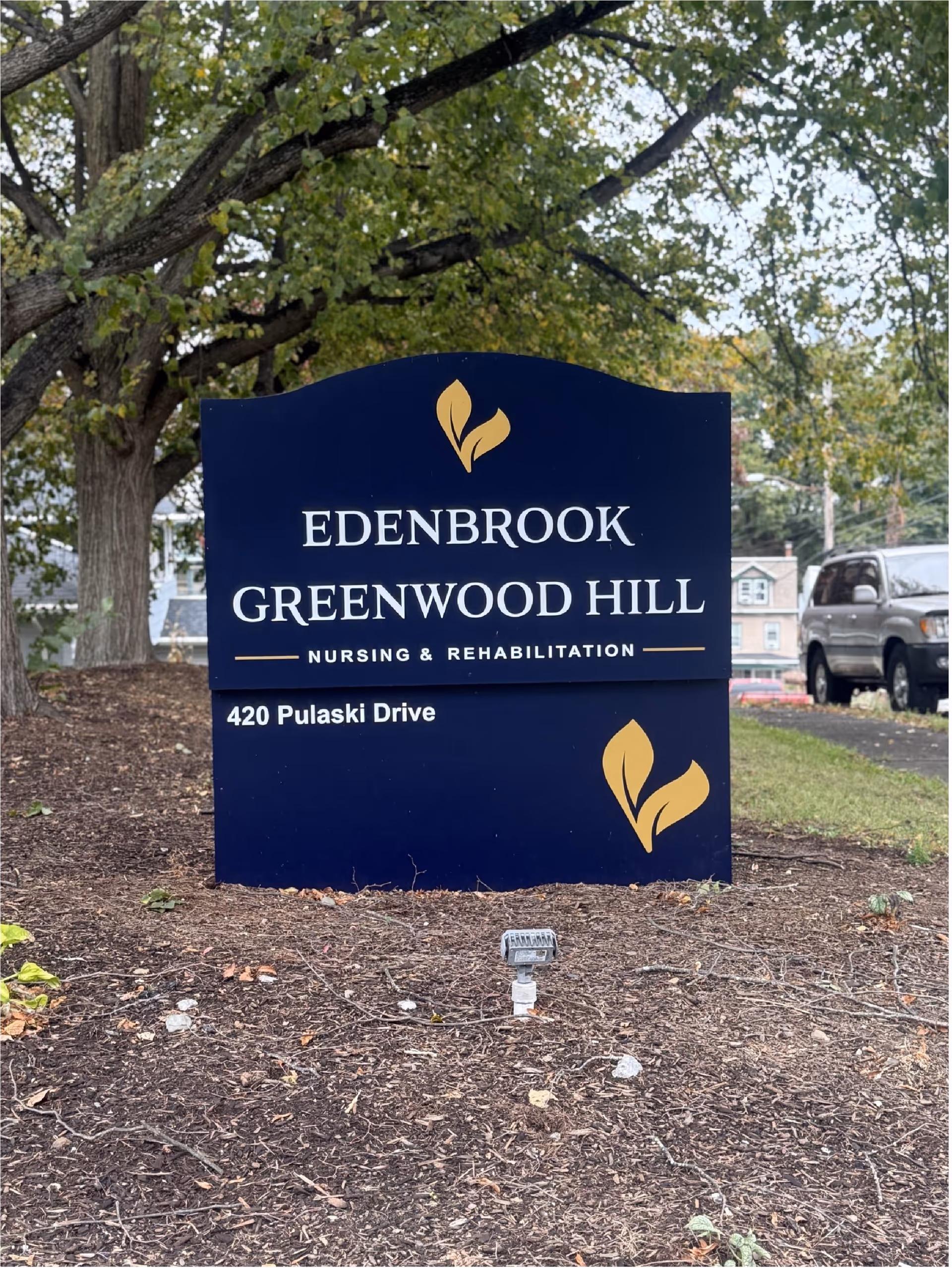 A dark blue sign for Edenbrook Greenwood Hill Nursing and Rehabilitation outdoors.