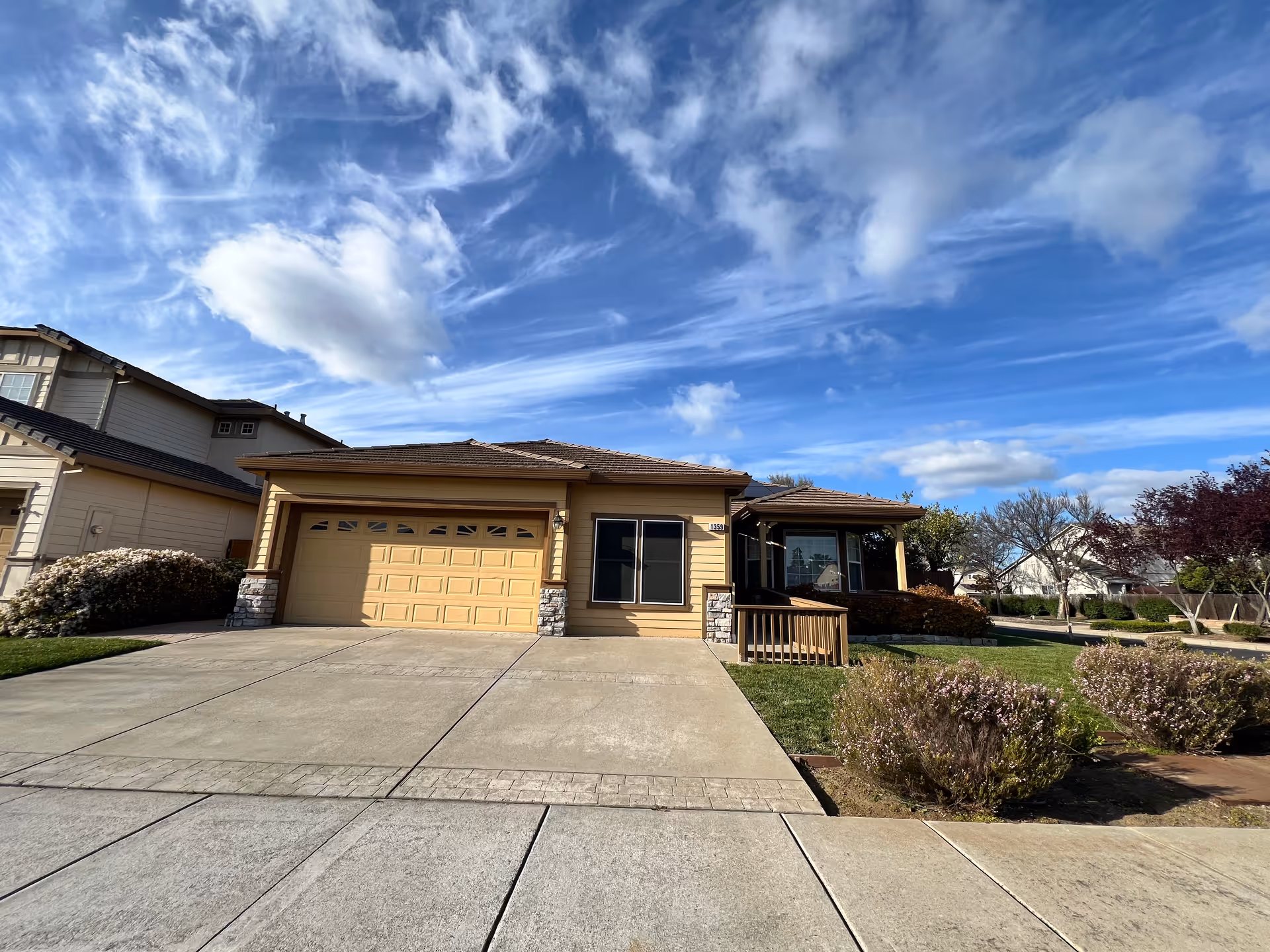 A beige, single-story house with a two-car garage and small front porch.