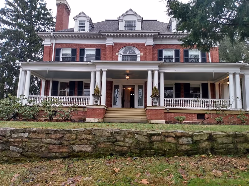 Brick colonial-style care home exterior with a wide front porch and columns.