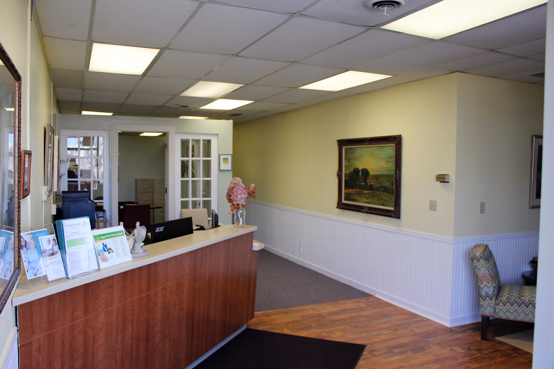 Reception desk with brochures in a care facility lobby, warm beige walls.