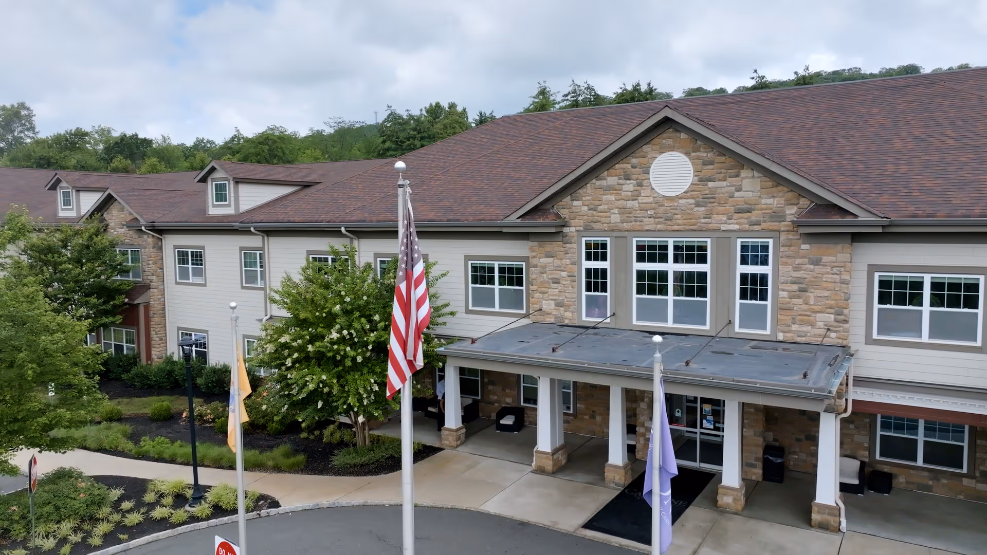Front view of CareOne at Somerset Valley Assisted Living building with flags and entrance.