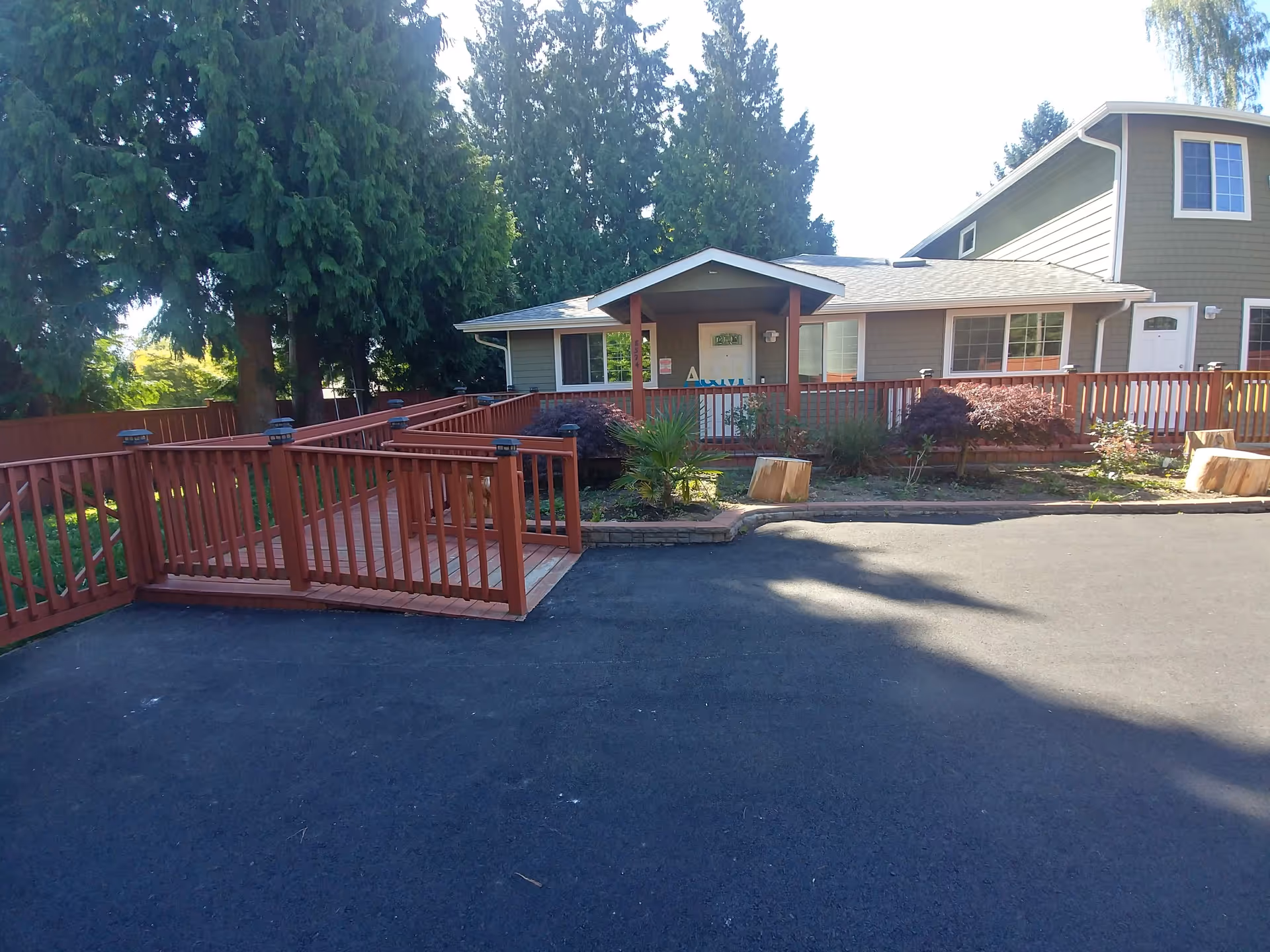 Exterior view of a senior living facility with a wooden ramp and landscaped yard.