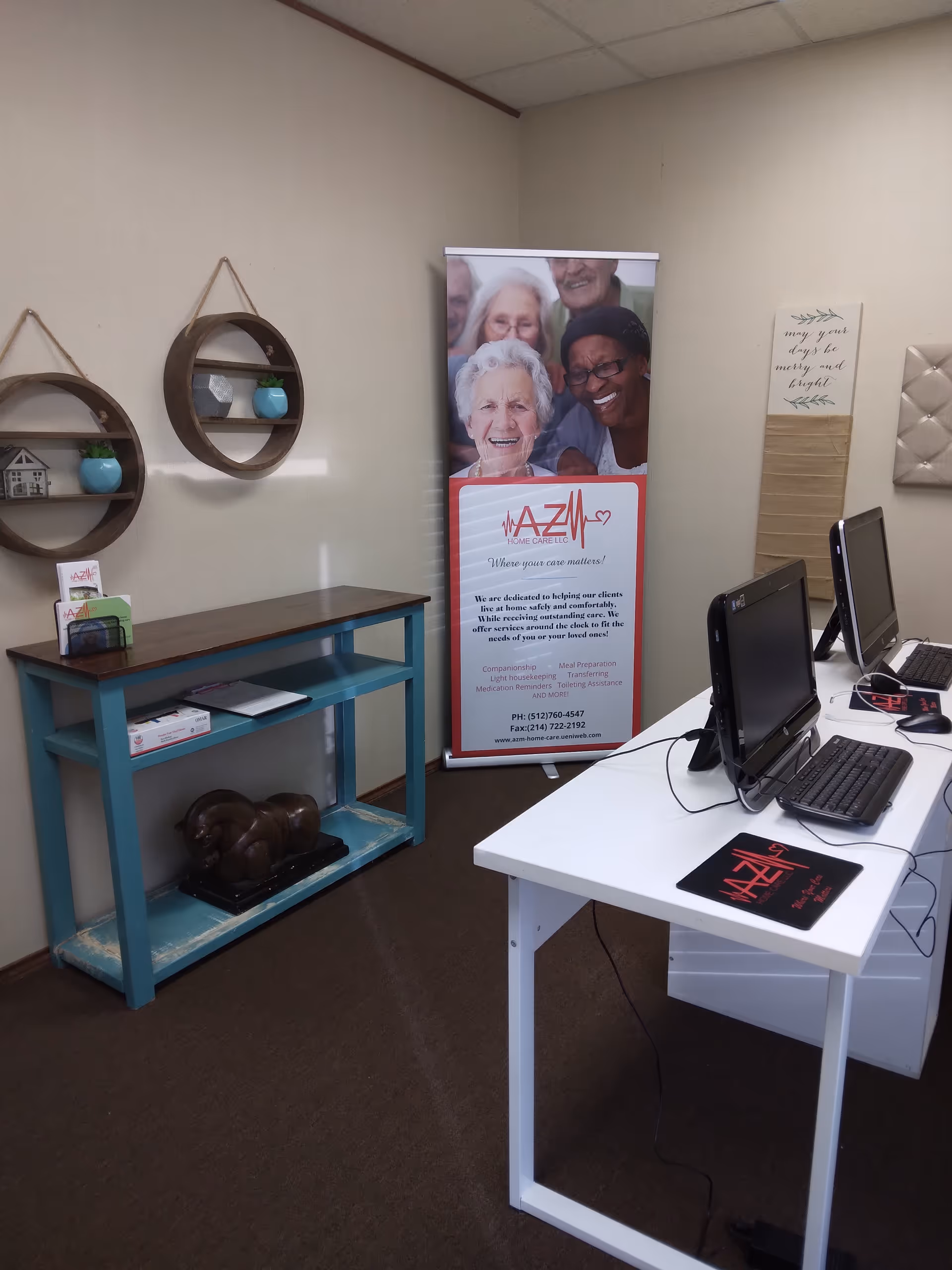 Interior office space with a white desk, computers, shelves, and AZM Home Care banner.