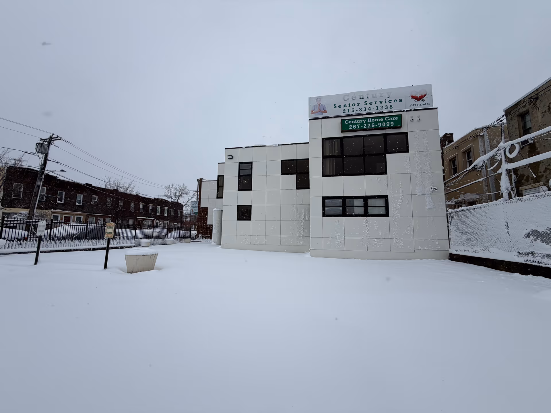 Snow-covered exterior of a Century Home Care building with signage in a quiet neighborhood.