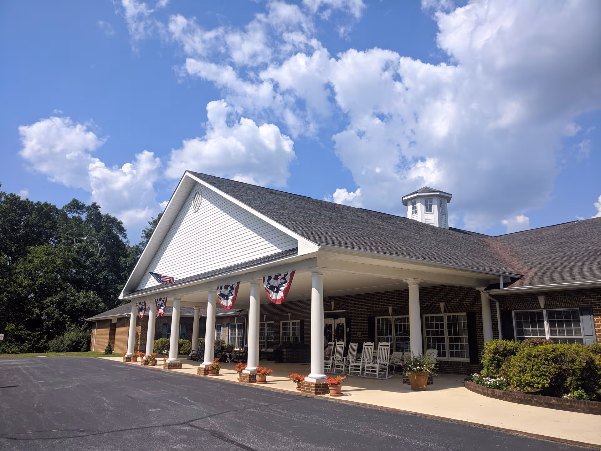 Front view of Hickory Hill Retirement Community entrance with white columns and rocking chairs