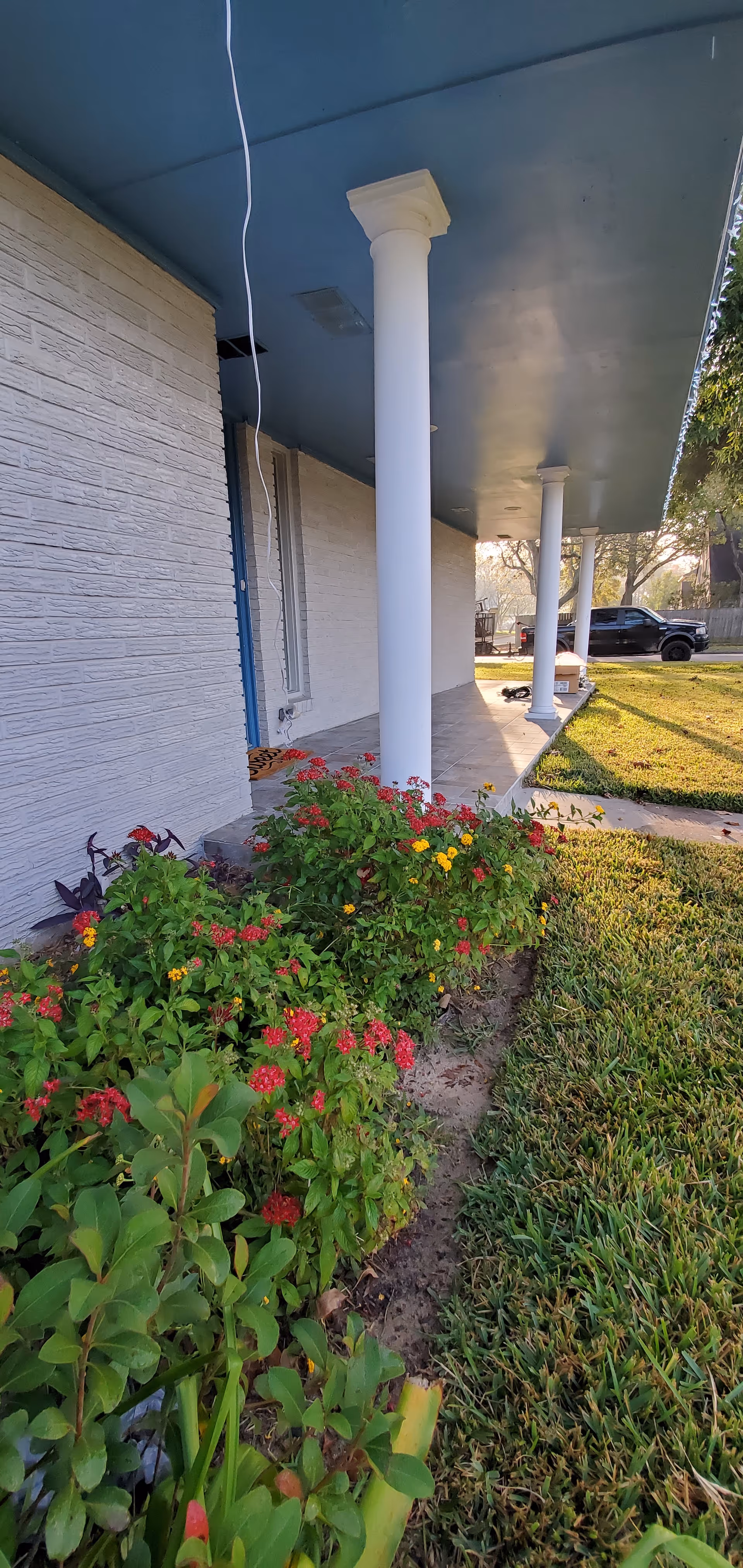 Exterior of a senior living facility with a covered walkway, columns, and flower beds.