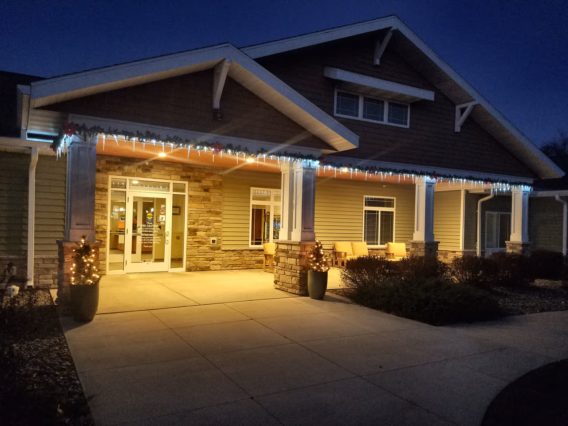 Nighttime exterior of Lake Hallie Memory Care featuring lit entry and porch seating.