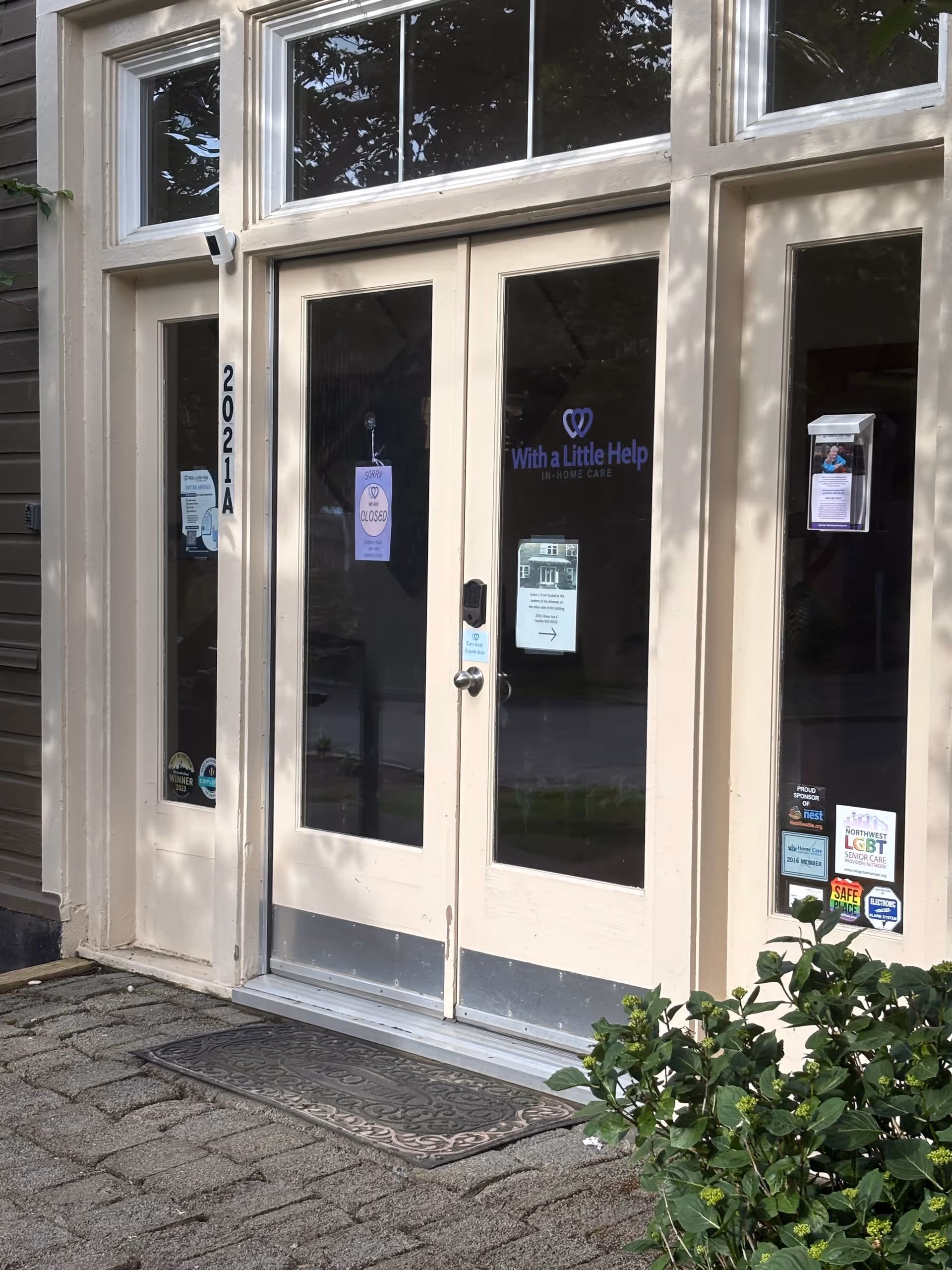 Entrance to With a Little Help senior living, beige doors and signage.