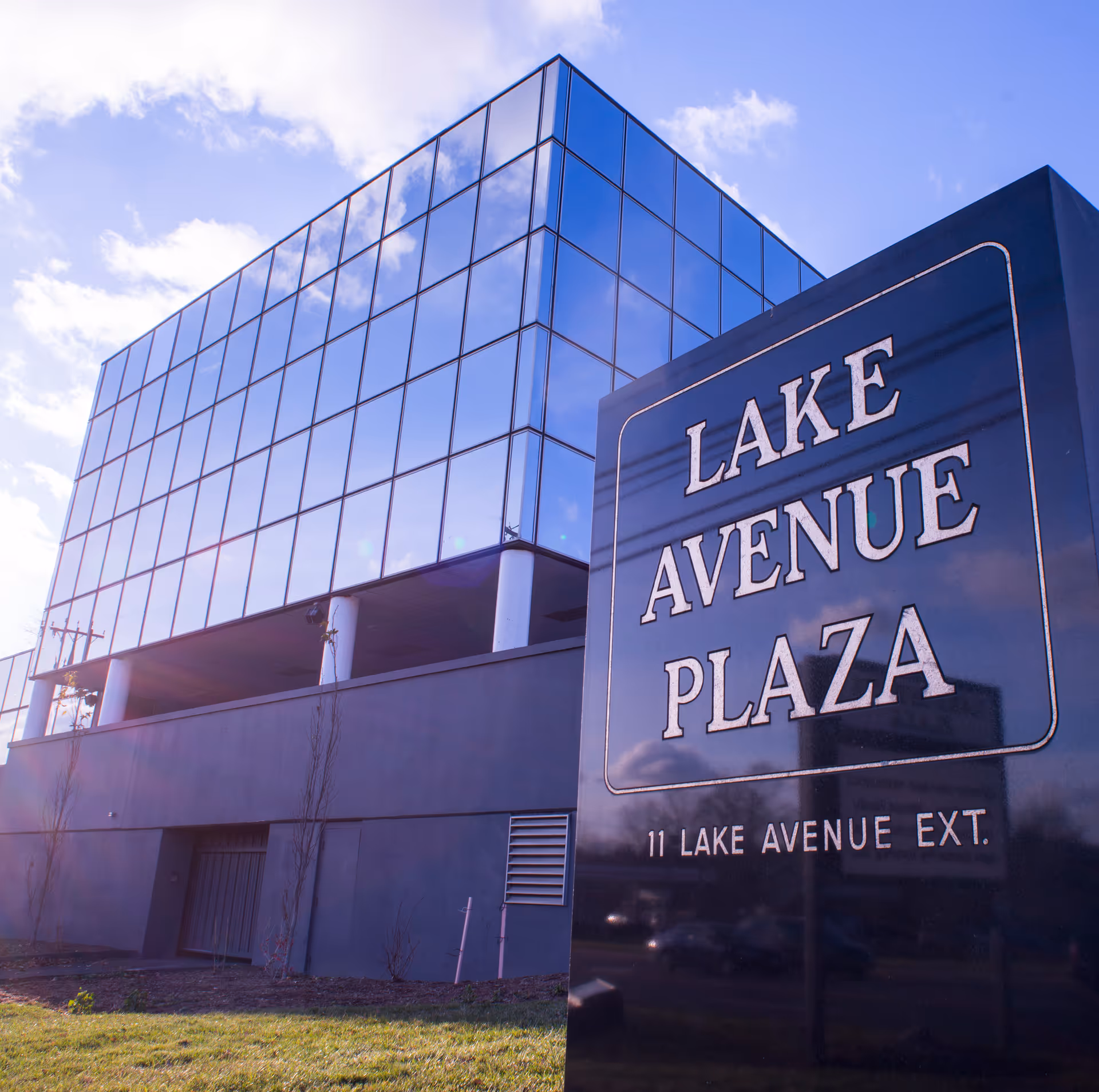 Glass-front building with a large Lake Avenue Plaza sign on the exterior.