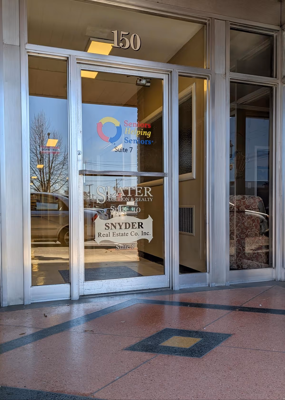 Glass entrance door labeled 150 with Seniors Helping Seniors sign and real estate branding.